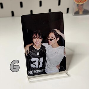 May include: A clear acrylic photo stand holding a photograph of two young men. One man wears a black and white jersey with the number 31 and the word "HOMEBOY". The other man wears sunglasses and a white t-shirt.
