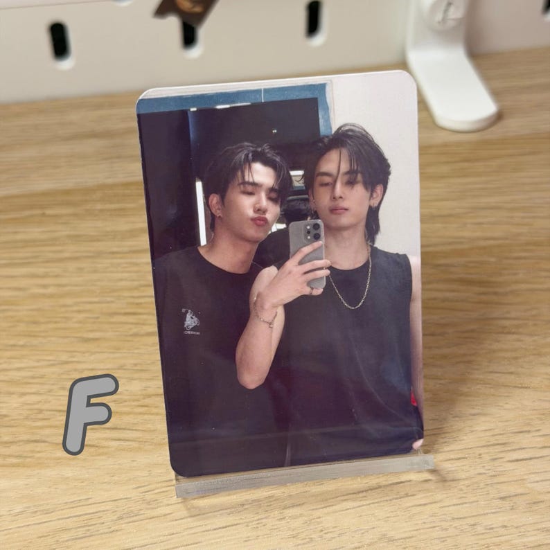 Peut inclure: Une photographie de deux personnes posant pour un selfie. Ils portent tous les deux des d&eacute;bardeurs noirs. La photo est affich&eacute;e dans un pr&eacute;sentoir en acrylique transparent sur une surface en bois. La lettre "F" est visible en bas &agrave; gauche.