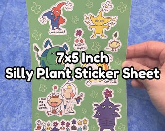 Könnte beinhalten: Ein 7x5 Zoll großer Aufkleberbogen mit verschiedenen Zeichentrickfiguren und Blumenmotiven auf grünem Hintergrund. Der Bogen enthält Texte wie Love wins, Small but Mighty, Hi, Oatch und I miss my wife, Louie, neben bunten Illustrationen.