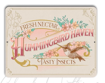 Puede incluir: Un letrero rectangular de aluminio de 23x30cm con un diseño vintage. El letrero presenta las palabras "Fresh Nectar" y "Hummingbird Haven" en una fuente decorativa, junto con una ilustración de colibrí y detalles florales. El letrero es de color crema con detalles rosas y dorados.