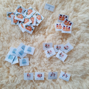 May include: A set of colorful illustrated cards with French words for daily activities, including "maison", "ecole", "cant", "nounou", "sport", "papi/mamie", and "centre de loisirs".