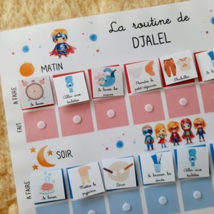 May include: A colorful chart with a superhero theme for a child's daily routine. The chart includes activities like getting dressed, brushing teeth, and eating breakfast. The chart is labeled "La routine de DJALEL".