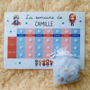 May include: A weekly chart for a child to track their daily activities. The chart is divided into morning, afternoon, and evening sections. Each day of the week is represented by a column with a superhero character at the top. The chart is printed on white paper with blue and pink accents. The chart includes the text "La semaine de CAMILLE".