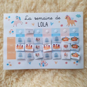 May include: A colorful weekly visual schedule for a child named Lola. The schedule includes activities like school, playtime, and home. The schedule is decorated with unicorns and stars.