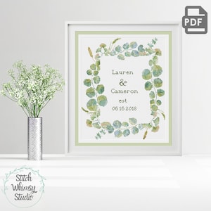 Peut inclure: Un motif de point de croix représentant une couronne de feuilles d'eucalyptus vertes avec le texte "Lauren & Cameron est 05 16 2018" au centre.