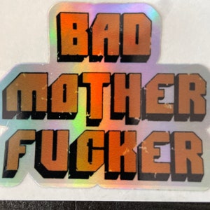 May include: A holographic sticker with the text "BAD MOTHER FUCKER" in orange letters with black outlines.