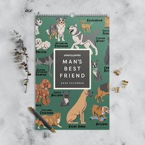 Puede incluir: Un calendario de 2026 con ilustraciones de varias razas de perros, incluyendo un Husky Siberiano, un Bulldog Francés y un Gran Danés, sobre un fondo verde. El calendario se titula "MAN'S BEST FRIEND" e incluye el logotipo de Smarty Prints.