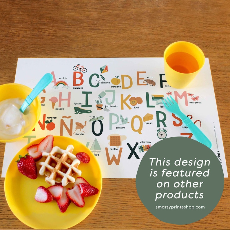 May include: A colorful placemat with the Spanish alphabet and illustrations of various objects. The placemat is yellow, blue, green, and red. The text on the placemat says "This design is featured on other products" and "smartyprintsshop.com".