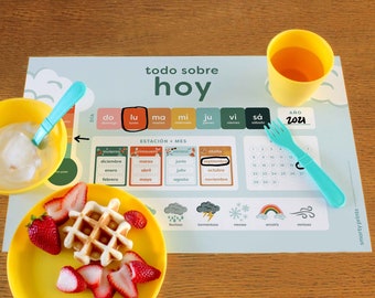 May include: A colorful placemat with a calendar, weather icons, and a section for the day of the week. The placemat also includes a section for the month and season. The placemat is designed to help children learn about the days of the week, months of the year, and seasons.