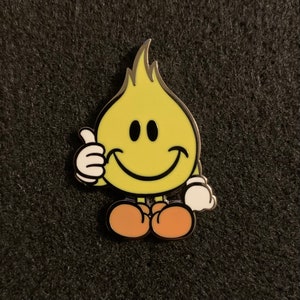 May include: A yellow cartoon character with a flame-shaped head, wearing white gloves and orange shoes, giving a thumbs up with a big smile.