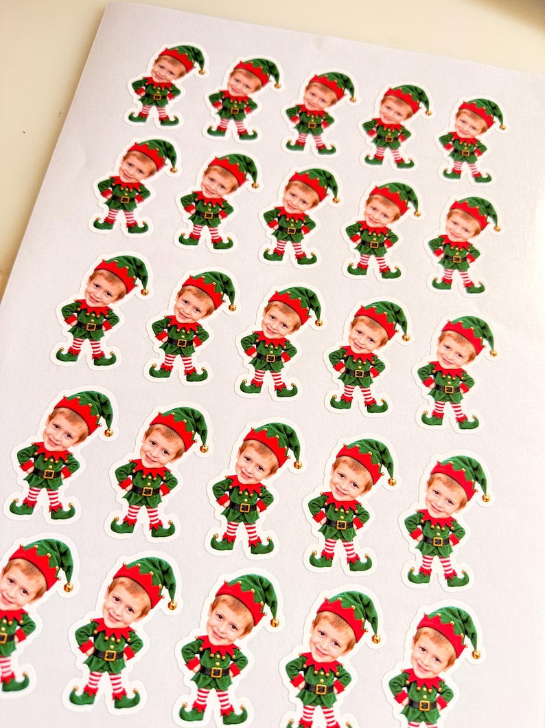 May include: A sheet of twenty-five identical stickers featuring a cartoon elf with a child's face. Each elf wears a green tunic, a green hat with a gold bell, and red and white striped leggings, standing with hands on hips.