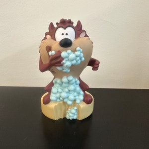 Op de afbeelding: Een bruin en beige Tazmanian Devil-figuur met blauwe en witte schuimzeep op een beige basis.