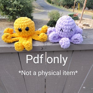 May include: Two crocheted octopus plushies, one yellow and one purple, with black eyes. The plushies are sitting on a wooden fence.