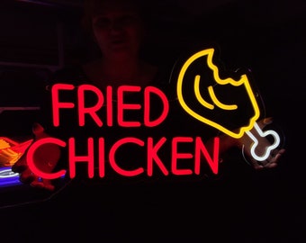 May include: Neon sign with the words "FRIED CHICKEN" in red and a yellow neon chicken leg with a white bone.