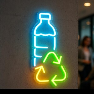 May include: A neon sign showing a blue outline of a plastic bottle above a green and yellow recycling symbol. The sign is mounted on a grey concrete wall, with two people blurred in the background.