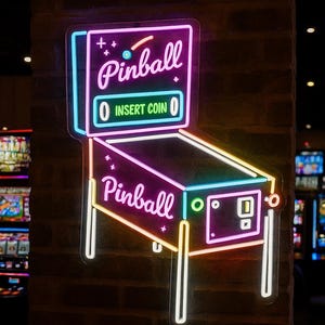 May include: Neon sign shaped like a pinball machine, with the word "Pinball" in pink neon. The sign has a blue and yellow outline, with the text "Insert Coin" in green. The sign is mounted on a brick wall.
