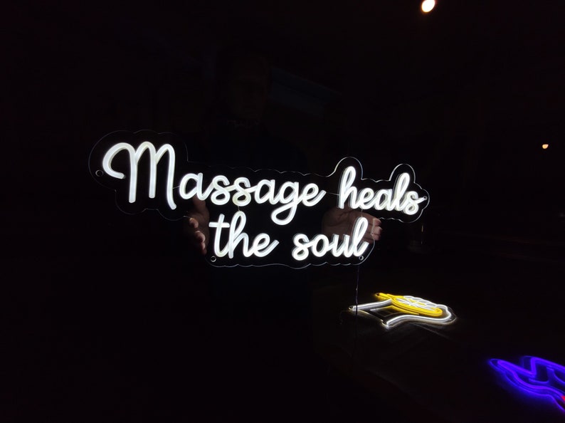 May include: White neon sign with the text "Massage heals the soul" in a cursive font.