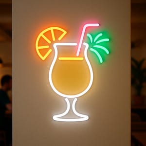 May include: A neon sign in the shape of a cocktail glass with a slice of orange, a straw, and a green garnish. The sign is lit with bright orange, pink, green, and white lights, creating a vibrant and eye-catching display. The cocktail glass is filled with a yellow liquid.
