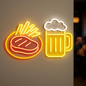 May include: Neon sign featuring a steak and fries, and a beer mug. The steak and fries are in a circular design, with the steak having grill marks. The beer mug has a foamy top. The sign is yellow and orange.