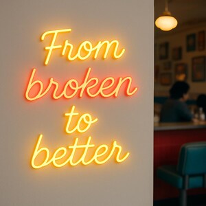 May include: A neon sign with the words "From broken to better" in a cursive font. The word "broken" is in a reddish-orange color, while "From", "to", and "better" are in yellow. The sign is mounted on a light-colored wall.