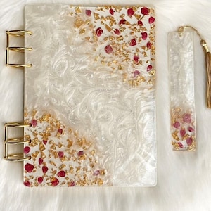 May include: White and gold marbleized journal with red and gold flakes and a matching bookmark with a gold tassel.