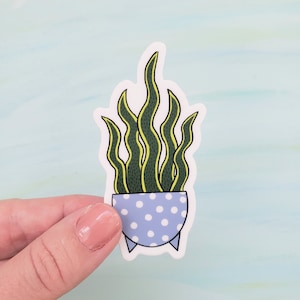 May include: A sticker of a potted plant with green leaves and a blue and white polka dot pot.