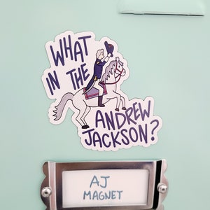 May include: A white magnet with a cartoon illustration of a man on a horse. The text "What in the Andrew Jackson?" is written in blue. The magnet is attached to a light blue locker with a silver nameplate that reads "AJ Magnet".