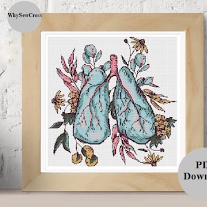 May include: Cross stitch pattern of a pair of lungs with floral accents. The lungs are blue and pink, and the flowers are yellow, pink, and green.