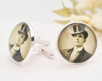 May include: Silver cufflinks featuring a sepia-toned portrait of a man in a top hat and suit. The round, polished metal cufflinks have a classic design, perfect for formal wear. The image is a vintage-style photograph.