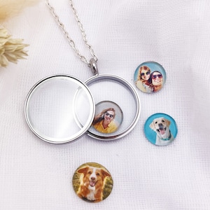 Könnte beinhalten: Eine silberne Locket-Halskette mit einem transparenten, runden Anhänger, der geöffnet ist, um ein kleines Foto zu zeigen. Drei weitere runde Fotos sind verstreut, jedes mit einem anderen Bild. Die Fotos sind wahrscheinlich kundenspezifisch, vielleicht für ein personalisiertes Geschenk.
