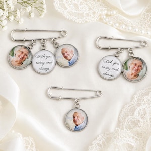 May include: Silver memorial pins with photo pendants. Each pin has a safety pin design with dangling circular pendants. Some pendants display a photo of a person, while others have the text "With you today and always."
