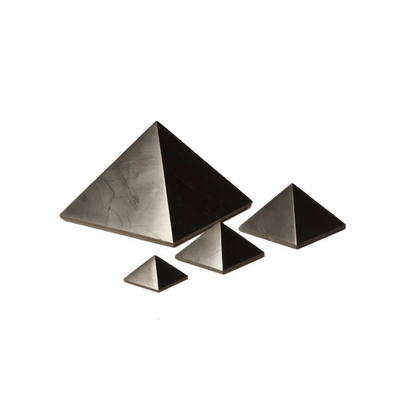 May include: Four black obsidian pyramids of varying sizes. The largest pyramid is in the center of the image, with the other three pyramids arranged around it.