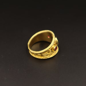 May include: A gold ring with intricate detailing and two red gemstones.