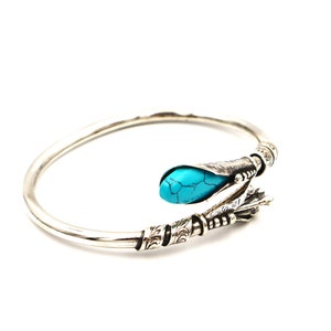 May include: A silver bangle bracelet with a turquoise stone set in a decorative silver design.