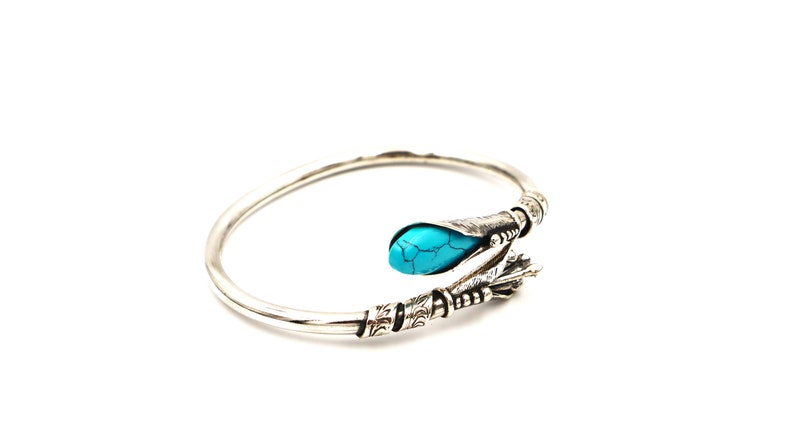 May include: A silver bangle bracelet with a turquoise stone set in a decorative silver design.