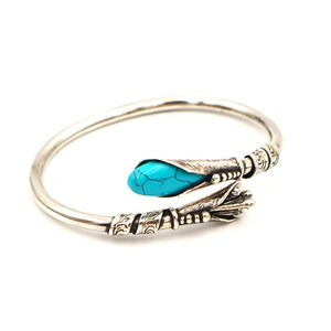 May include: A silver bangle bracelet with a turquoise stone set in a decorative silver design.