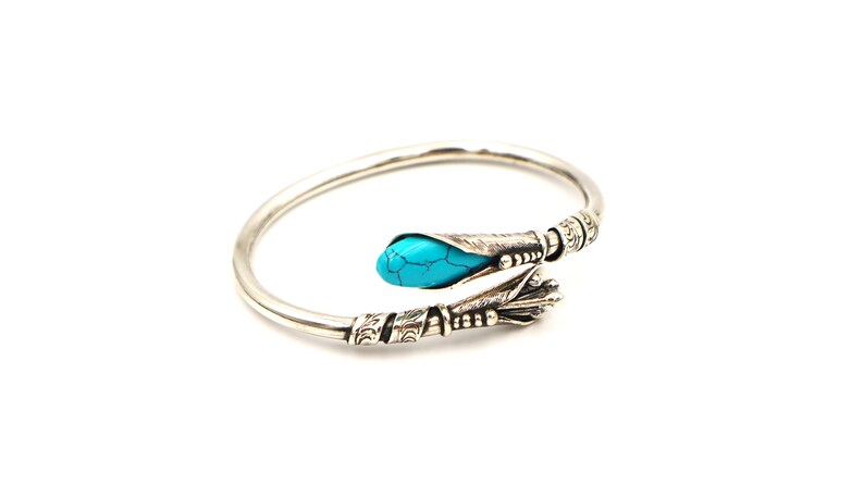 May include: A silver bangle bracelet with a turquoise stone set in a decorative silver design.