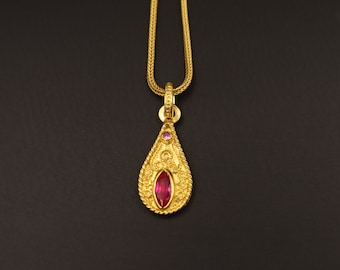 May include: A gold pendant necklace with a teardrop-shaped pendant featuring a red gemstone and smaller pink gemstones.