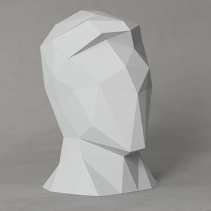 Peut inclure: Une sculpture géométrique blanche représentant une tête humaine. La sculpture est en papier et présente un design triangulaire.
