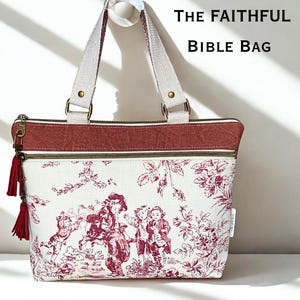 May include: A tote bag labeled The Faithful Bible Bag with a cream and burgundy toile pattern featuring figures and floral motifs. It has a solid burgundy top panel, two cream canvas handles, a zippered closure, and two burgundy tassels on the zipper.