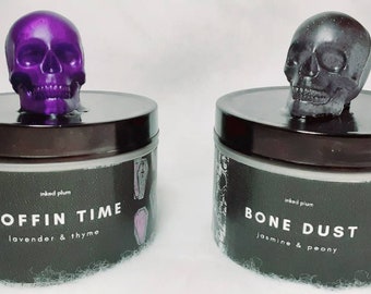 May include: Two decorative jars with skull-shaped lids. One jar has a purple skull, the other a dark gray skull. The jars have black labels with white text that reads "COFFIN TIME" and "BONE DUST". The jars are themed for Halloween.