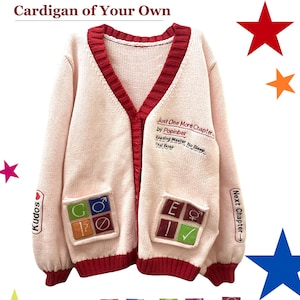 May include: A light pink knit cardigan with a deep red ribbed V-neck collar and cuffs. The front features embroidered text including "Just One More Chapter" and "Popinber". Two front pockets display colorful square patches with symbols.
