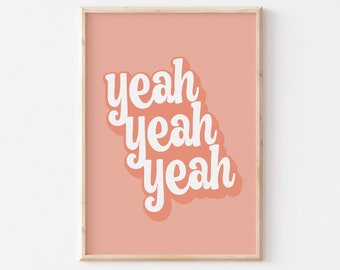 May include: A framed print with a peach background and white text that reads "yeah yeah yeah" in a retro font.