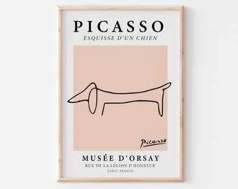 May include: A framed print of a black and white line drawing of a dachshund by Pablo Picasso. The print is on a light pink background and includes the text "PICASSO", "ESQUISSE D'UN CHIEN", "MUSÉE D'ORSAY", "RUE DE LA LÉGION D'HONNEUR", and "PARIS, FRANCE".