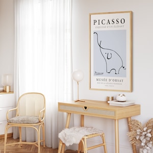 May include: A framed print of a black and white line drawing of an elephant by Pablo Picasso. The print is titled "Esquisse d'un &Eacute;l&eacute;phant" and includes the artist's signature and the museum's name, "Mus&eacute;e d'Orsay".