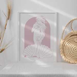 Peut inclure: Une impression encadr&eacute;e blanche d'un dessin au trait de la Naissance de V&eacute;nus, un c&eacute;l&egrave;bre tableau de la Renaissance. L'impression est sur fond rose et repr&eacute;sente une femme debout sur une coquille.