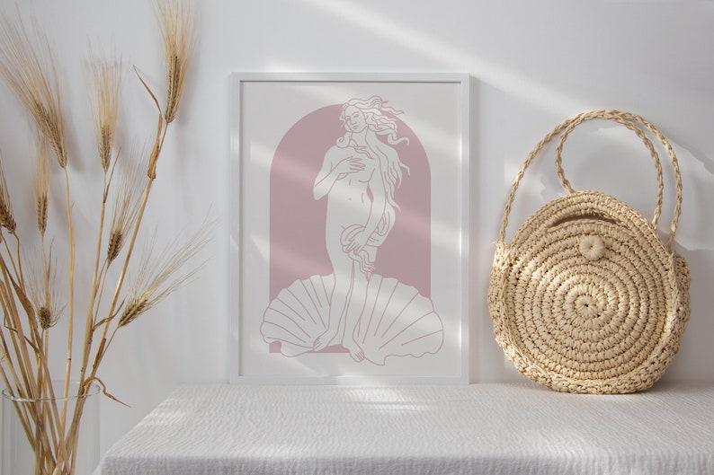 Peut inclure: Une impression encadr&eacute;e blanche d'un dessin au trait de la Naissance de V&eacute;nus, un c&eacute;l&egrave;bre tableau de la Renaissance. L'impression est sur fond rose et repr&eacute;sente une femme debout sur une coquille.