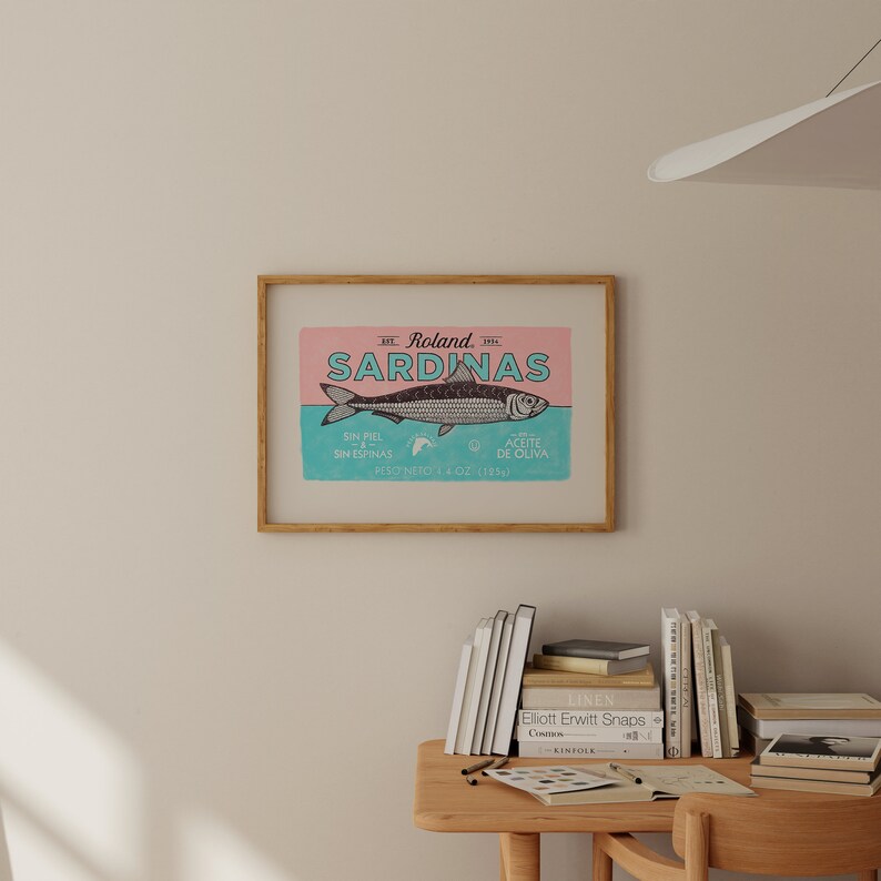 May include: A vintage-style illustration of a sardine can label with the text "Roland Sardinas" in a blue and white font. The label is pink and blue with a drawing of a sardine in the center. The text below the sardine reads "Sin Piel Sin Espinas Aceite de Oliva Peso Neto 4 OZ (1854)"