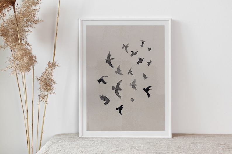 Pu&ograve; includere: Una stampa incorniciata con un design minimalista che presenta un gruppo di uccelli neri in silhouette su uno sfondo beige chiaro.