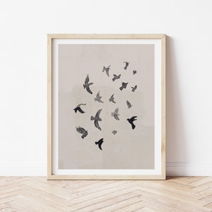 Pu&ograve; includere: Una stampa incorniciata con un design minimalista che presenta un gruppo di uccelli neri in volo su uno sfondo beige chiaro.